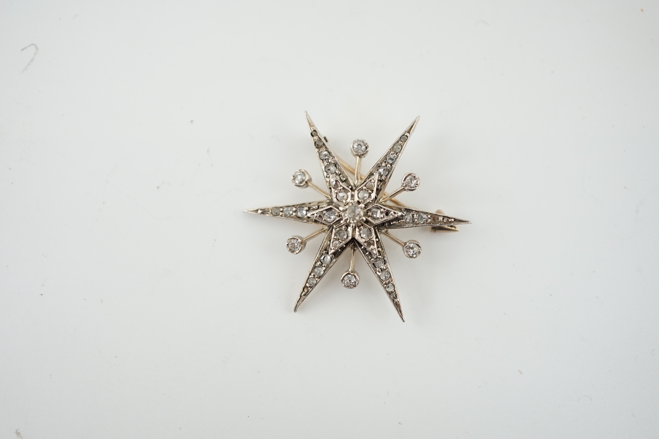 A Victorian style gold, silver and rose cut diamond cluster set starburst brooch